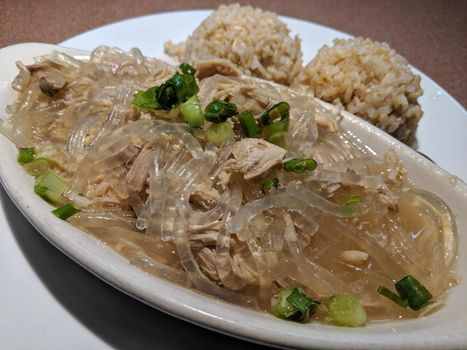 Chicken Long Rice and two scoops of brown rice on a plate on table.