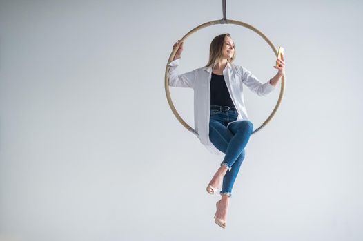 Caucasian woman gymnast on an aerial hoop takes a selfie on a smartphone