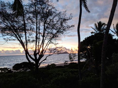 Early Morning Sunrise on Waimanalo Beach on Oahu, Hawaii over ocean by Rabbit and Rock Island bursting through the clouds. 