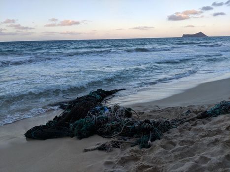 Bundle of Plastic Fishing Nets and lines washes up on Waimanalo Beach with Rabbit Island in the distance on Oahu, Hawaii.