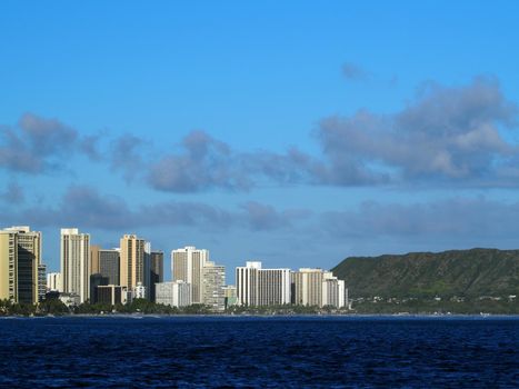 Waikiki Hotels and Diamond Head Crater during the day along the shore seen from the ocean on Oahu, Hawaii.