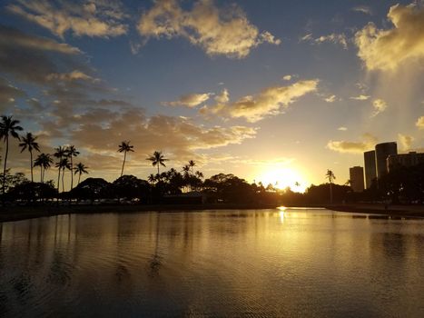 Sunset over pond surrounded by coconut trees at Ala Moana Beach Park on Oahu, Hawaii.