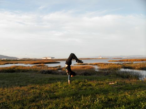 Man does a Handstand in the Marshes outside of SFO Airport in San Francisco, California.