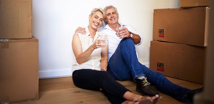 May your home be as happy as ours is. a mature couple toasting with water after a successful day moving house