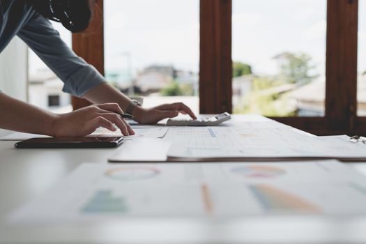 Close up Business woman using calculator for do math finance on wooden desk in office and business working background, tax, accounting, statistics and analytic research concept