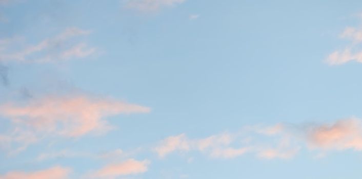 Background of blue sky with pale pink clouds at sunset