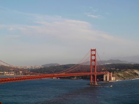 Tug boat sails under Golden Gate Bridge with San Francisco Cityscape, taken from the Marin Headlands hills.