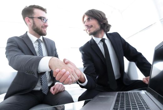 colleagues shaking hands in front of the open laptop . photo has copy space.
