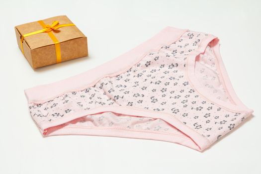 Pink cotton panties and a gift box on the white background. Woman underwear set. Top view.