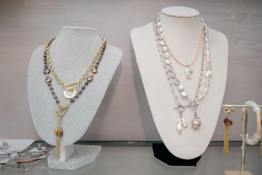 Shop window with necklaces and jewelry. Custome jewelry on display.Variety of colorful necklaces, bracelets, earrings, rings in window of costume jewelry store