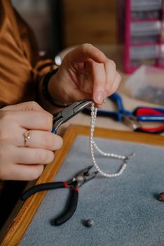 Jewelry making and beading process.The process of making jewelry.A woman makes jewelry in a workshop.Fashion, creativity and handmade concept