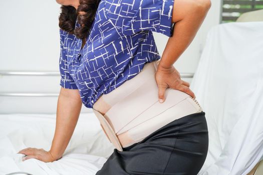 Asian senior wearing elastic support belt can help reduce back pain.
