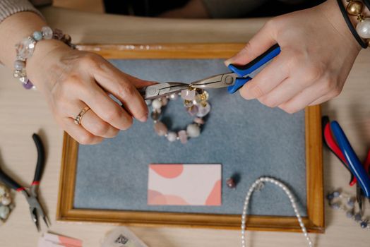 Jewelry making and beading process.The process of making jewelry.A woman makes jewelry in a workshop.Fashion, creativity and handmade concept