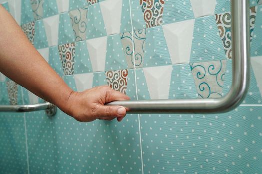 Asian woman patient use toilet support rail in bathroom, handrail safety grab bar, security in nursing hospital.