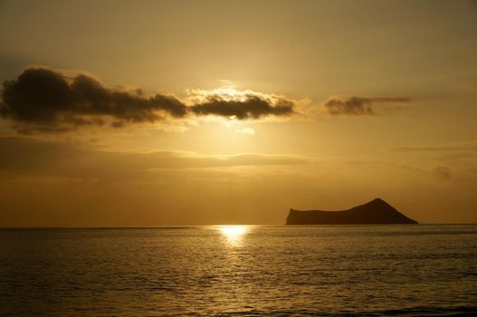 Sunrise on Waimanalo Bay on Oahu, Hawaii over ocean by Rabbit Island bursting through the clouds. 