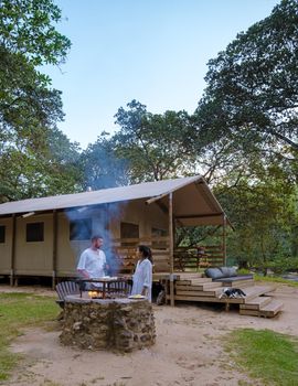 Budget Safari tent in South Africa for family vacations in nature, Safari tented camp in green forest bush nature. Asian women and European men camping