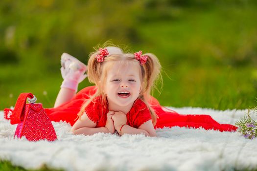 little girl in a red dress lies on a white blanket