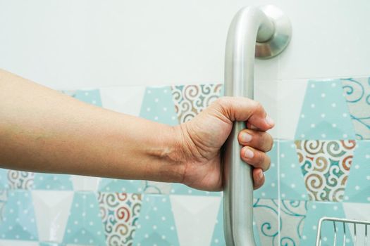Asian woman patient use toilet support rail in bathroom, handrail safety grab bar, security in nursing hospital.