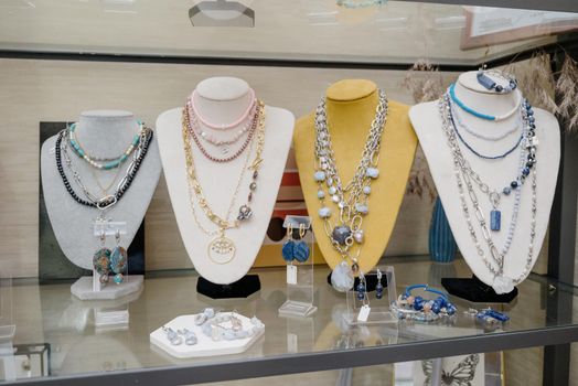 Shop window with necklaces and jewelry. Custome jewelry on display.Variety of colorful necklaces, bracelets, earrings, rings in window of costume jewelry store