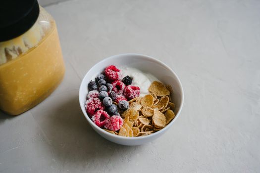 Healthy breakfast with berries, cereals and natural yogurt. Multi-lacquered cereals for breakfast. Berries in ice. Frozen raspberries and black currants. A jar of peanut butter.