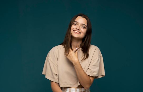 Attractive excited young brunette girl wearing casual clothing standing isolated over blue background, looking at camera