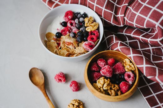 Plate with natural yogurt, cereals and berries. Delicious and healthy breakfast. Proper nutrition. Black currant and raspberry frozen.