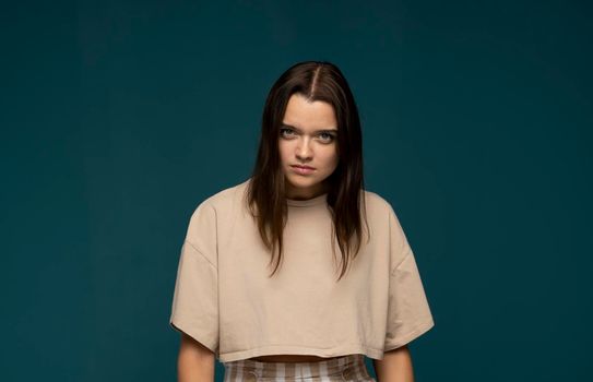 Portrait of an upset unsatisfied brunette woman looking in the camera isolated over blue background