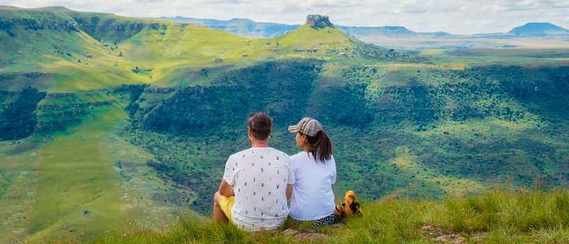 Young couple man and woman hiking in the mountains, Drakensberg Giant Castle South Africa, Drakensberg mountain,l Drakensberg Kwazulu Natal, green mountains in South Africa, a young Asian woman hiking