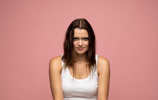 Gloomy insulted timid girl feeling offended and displeased, pouting upset on a pink background