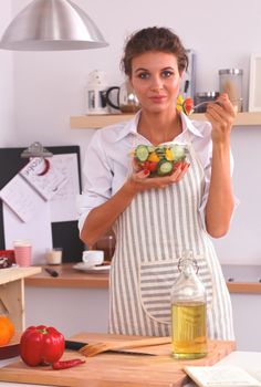 Woman eating fresh salad in modern kitchen