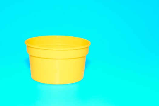 a wide mouthed cylindrical container made of glass or pottery and typically having a lid, used especially for storing product. Yellow plastic jar capacity of isolated on blue azure. High quality photo