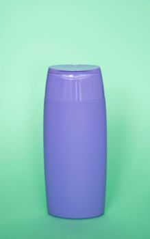 Violet plastic bottle of body care and beauty products. Studio photography of plastic bottle for shampoo, shower gel, creme isolated on green background