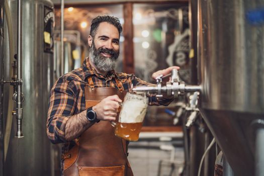 Brewery master tasting beer in production facility. Small family business, production of craft beer.