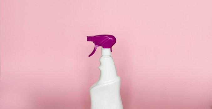 White plastic spray bottle for liquid cleaning products isolated on pink background. Packaging mockup bottle with violet sprayer