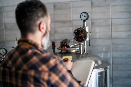 Man is working at craft beer factory. He is operating machinery in brewery. Small family business, production of craft beer.