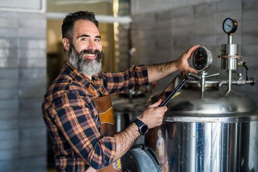 Man is working at craft beer factory. He is operating machinery in brewery. Small family business, production of craft beer.