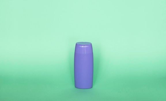 Violet plastic bottle of body care and beauty products. Studio photography of plastic bottle for shampoo, shower gel, creme isolated on green background
