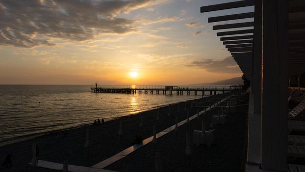 LAZAREVSKOE, SOCHI, RUSSIA - MAY, 26, 2021: Orange saturated sunset with silhouettes of people on the background of the sun.