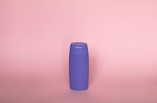Violet plastic bottle of body care and beauty products. Studio photography of plastic bottle for shampoo, shower gel, creme isolated on pink background