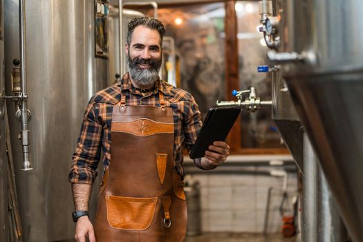 Man is working at craft beer factory. He is operating machinery in brewery. Small family business, production of craft beer.