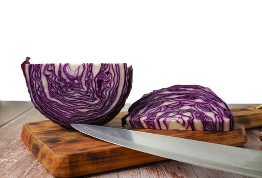 close-up of a red cabbage or purple cabbage cut with a knife on a wooden board