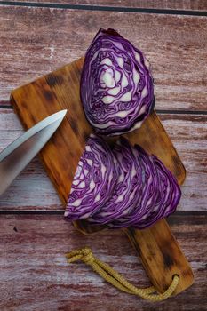 close-up of a red cabbage or purple cabbage cut with a knife on a wooden board