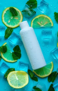 Bottle with cosmetics on a mint background with ice cubes and lemon. Selective focus. Spa.