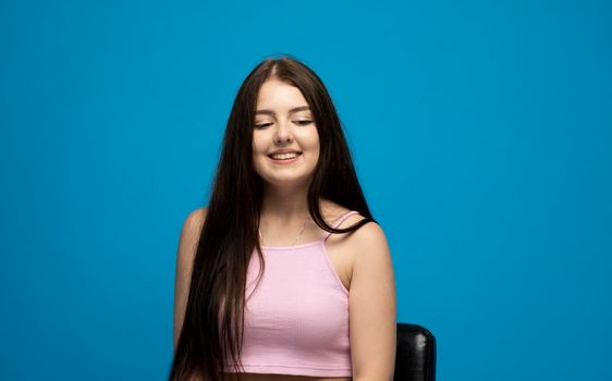 Beautiful cute gergerous brunette girl with long hair in a casual pink t-shirt looking down