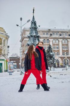 young family guy and girl spend the day in the park on a snowy day. Emotional young couple having fun while walking in the winter city, a lively man hugs his laughing beautiful woman