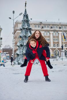 young family guy and girl spend the day in the park on a snowy day. Emotional young couple having fun while walking in the winter city, a lively man hugs his laughing beautiful woman