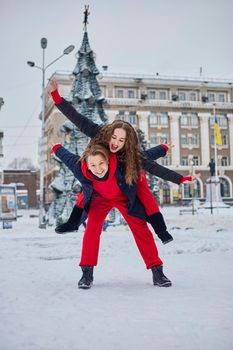 young family guy and girl spend the day in the park on a snowy day. Emotional young couple having fun while walking in the winter city, a lively man hugs his laughing beautiful woman