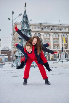 young family guy and girl spend the day in the park on a snowy day. Emotional young couple having fun while walking in the winter city, a lively man hugs his laughing beautiful woman