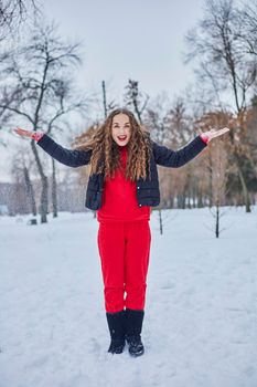 a young happy woman is having fun in a winter park, throwing snow, it is cold in her hands, the emissions are off scale