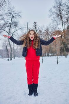 a young happy woman is having fun in a winter park, throwing snow, it is cold in her hands, the emissions are off scale